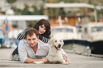 Young couple playing with a dog in the harbor