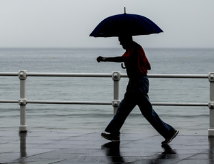 anciano con paraguas paseando por la ciudad