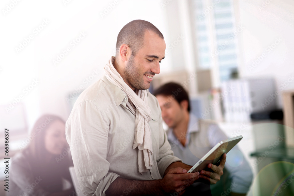 Wall mural Smiling man in office using digital tablet