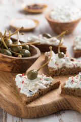 Fototapeta na wymiar toasts with cheese pate and capers on a wooden board, vertical