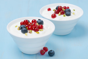 two bowls of fresh sweet yogurt with berries and pistachios