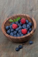 wooden bowl with fresh blueberries and raspberries, vertical