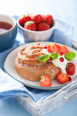 sweet cinnamon roll with cream and strawberry for breakfast