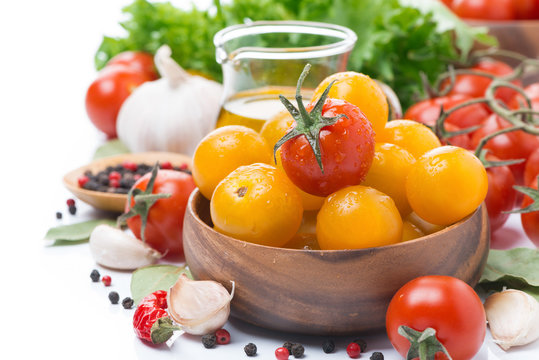 yellow and red cherry tomatoes in wooden bowl, olive oil, herbs