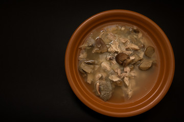 Mushroom soup with onions and chicken on a black background
