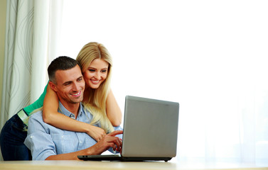 Happy couple using laptop together at home