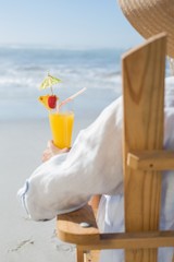 Woman relaxing in deck chair by the sea holding cocktail