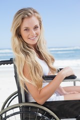 Wheelchair bound blonde smiling at the camera on the beach