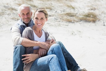 Attractive couple smiling at each other on the beach
