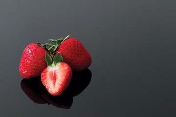 Fresh strawberries, dark reflective background
