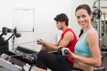 Fototapeta na wymiar Smiling brunette working out on the rowing machine