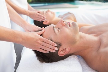 Obraz na płótnie Canvas Content couple enjoying head massages poolside