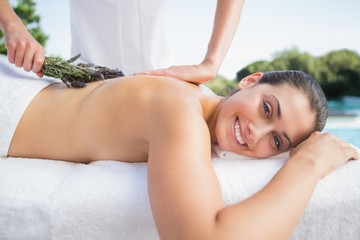 Obraz na płótnie Canvas Smiling brunette getting an aromatherapy treatment poolside