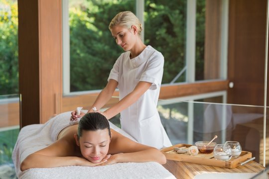 Content brunette enjoying a herbal compress massage