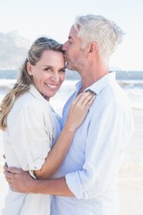Obraz premium Man kissing his smiling partner on the forehead at the beach