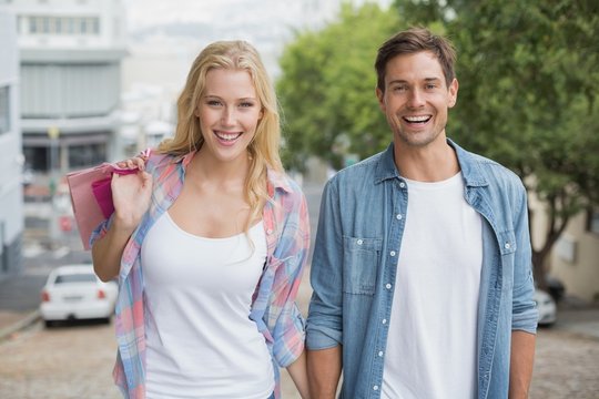 Hip young couple on shopping trip walking uphill
