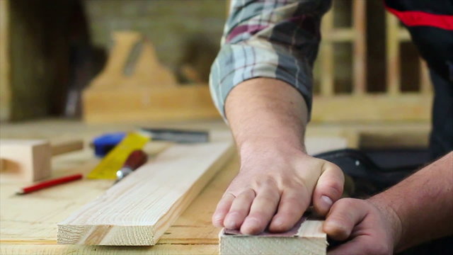 Close up of carpenter hands sanding wood in workshop.