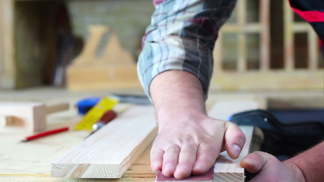 Close up of carpenter hands sanding wood in workshop.