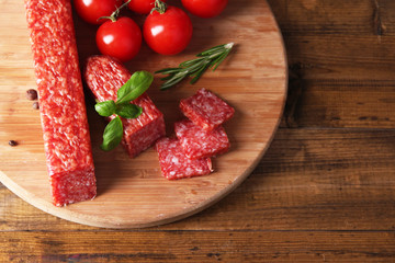 Tasty salami sausage and spices on wooden background
