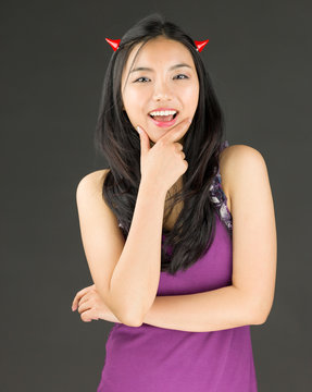 Devil side of a young Asian woman standing with hand on chin and