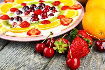 Homemade sweet pizza with fruits on wooden table, close up