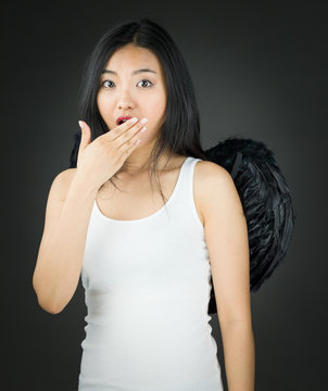 Shocked Asian young woman dressed up as an angel with hand over