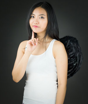 Asian young woman dressed up as an angel thinking with finger on