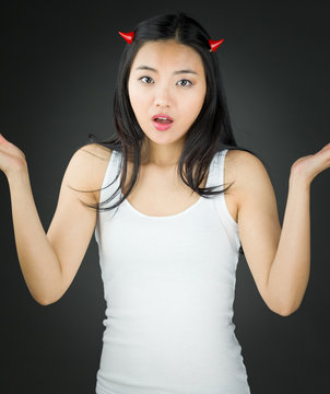 Asian young woman in devil horns don't know what to do