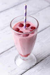 Glass of raspberry smoothie drink on wooden background