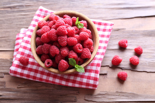 Ripe sweet raspberries in bowl on table close-up