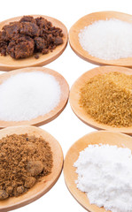 Various type of sugar on wooden spoon over white background