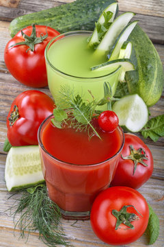 Healthy domestic tomato and cucumber  juices on a wooden table