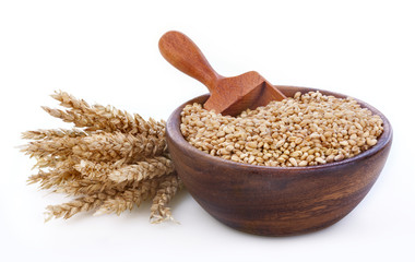Ripe wheat in a wooden bowl on white background
