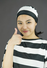 Young Asian woman showing thumb up sign in prisoners uniform