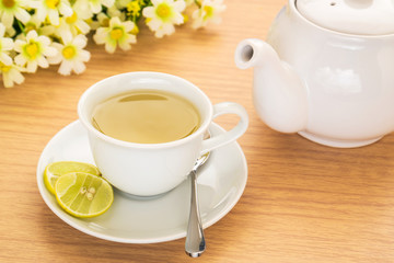 Fototapeta na wymiar Tea cup with lemon and pot on table