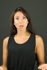 Shocked young woman shrugging with arms outstretched