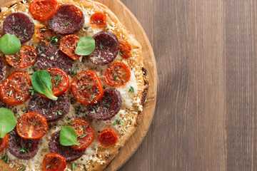 Italian pizza with salami and tomatoes on wooden table