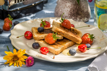 Close-up on toast with fruit and honey served in the garden