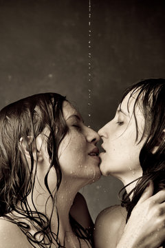 Two naked girls wet kiss on a dark background