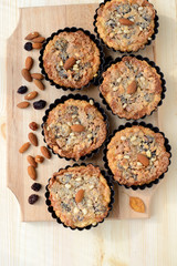Small tarts with nuts and raisins filling on a wooden board.