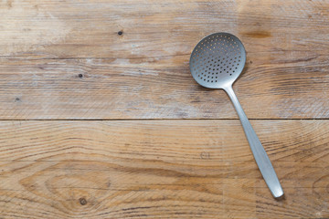 Abtropfkelle auf rustikalem Holzhintergrund in Vogelperspektive