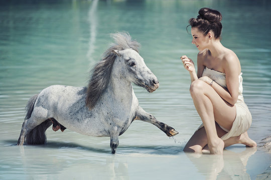 Alluring woman playing with the pony in the pool