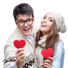 young cheerful casual couple holding red hearts