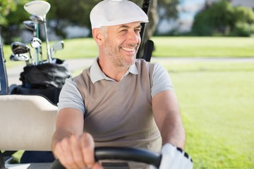 Happy golfer driving his golf buggy