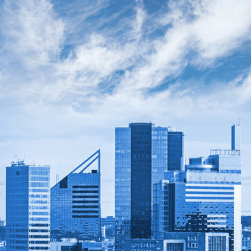 Blue cityscape with modern office buildings and cloudy sky