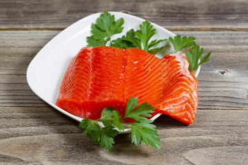 Fresh Salmon Fillet in white dish on rustic wood