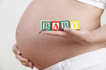 Pregnant Woman Holding Wooden Blocks Spelling Baby