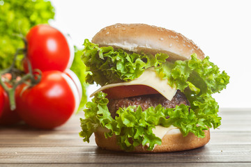 Cheeseburger with lettuce, onions and tomato in a sesame bun