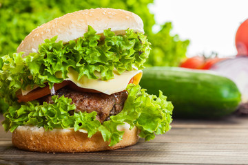 Cheeseburger with lettuce, onions and tomato in a sesame bun