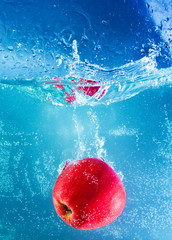 red apple dropped into water with splash